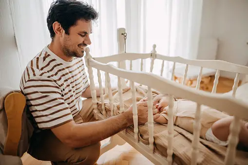 Father taking care of his newborn in crib