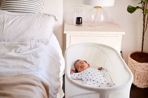 three month old baby asleep in his cot beside the bed in his bedroom